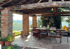 Relax in a serene outdoor space with a brick column structure, wooden pergola, and stone floor, perfect for dining and taking in the lush views.