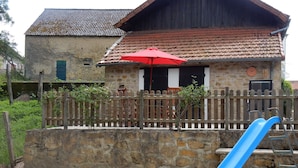 A stone building with a red-tiled roof, a wooden fence, and a blue slide. - Beautiful, quiet, Burgundy village location close to local amenities. (Panneçot)