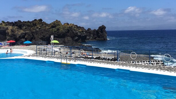 A swimming pool with a view of the ocean and rocky cliffs.