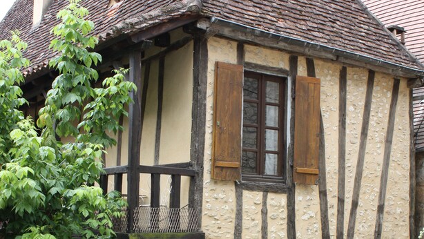 Ein traditionelles Fachwerkhäuschen mit Steinunterbau, Holzbalkonen und einem kleinen Balkon.