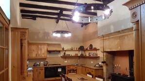 Eine traditionelle Küche mit Holzschränken, einem Esstisch und einem Kamin.