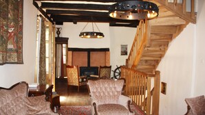 Ein traditionell eingerichtetes Wohnzimmer mit einem gemusterten Sofa, einem gepolsterten Sessel und einer Holztreppe.