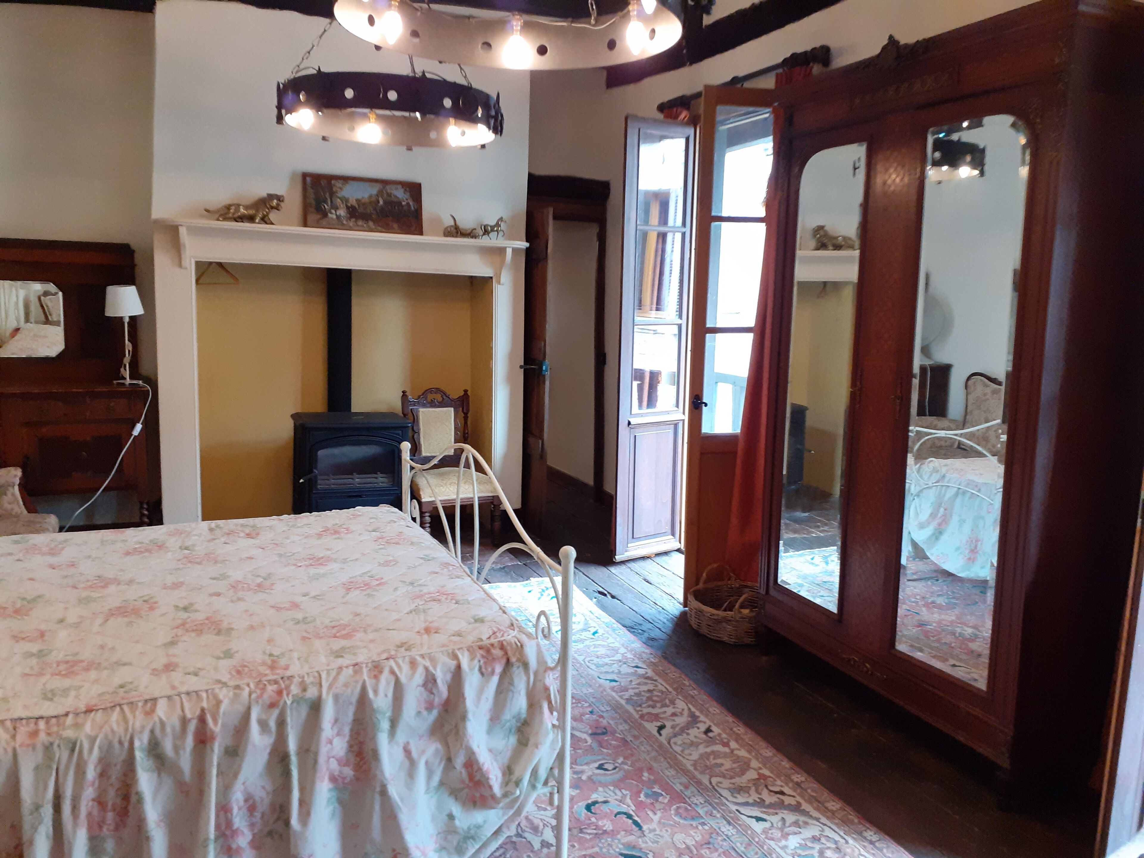 A bedroom with a bed, a dresser, a mirror, and a fireplace.