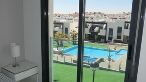 A hotel room with a large sliding glass door leading to a swimming pool and a view of other buildings. - Holiday Houses - Los Altos 92 (Torrevieja)