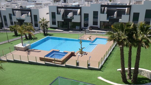 A modern pool area with a rectangular pool, surrounded by artificial grass and palm trees. - Holiday Houses - Los Altos 92 (Torrevieja)