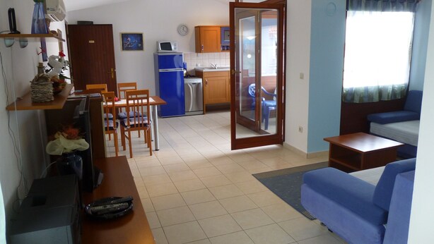 A compact living space with a kitchenette, a dining area, and a seating area with a sofa and chairs. - APARTMENT GROZIĆ **** PORAT - KRK  (MALINSKA)