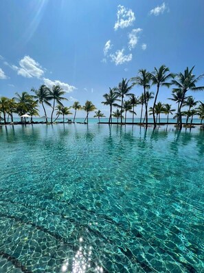 Ein klares Schwimmbecken mit Palmen und Blick auf den Ozean.