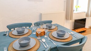A dining area with a table set for four, including bowls, glasses, and cutlery. - Granary - 17th century converted cottage (Looe)