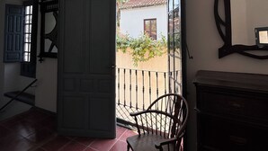 En åben dør, der fører ud til en balkon med en stol og et kommode.