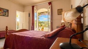 A bedroom with a bed, a desk with a lamp, a window with curtains, and a painting on the wall. - An Old Mas in Provence, Sun and Swimming Pool (Cabannes)