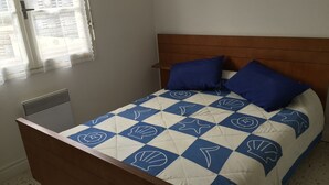 A bed with a blue and white quilt, two blue pillows, and a wooden headboard. - For rent T2- Leucate plage - 1er D- Front de mer (Leucate)