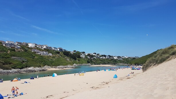 A beach with tents and umbrellas, a sandy shore, and houses on a hillside. - Little Croft - Spacious cottage in Woodland setting close to fantastic beaches (Truro)
