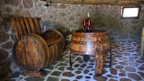 Une pièce rustique aux murs de pierre, avec une table faite d’un tonneau en bois et une chaise en bois.