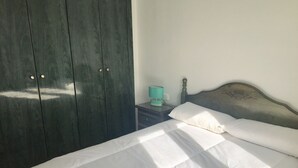 A bedroom with a bed, a nightstand, a lamp, and a wardrobe.