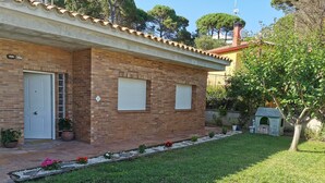 A two-story brick house with a tiled roof, a front door, and a small garden with a playhouse. - Fantastic House with Private Pool in Lloret de Mar (Vidreres)