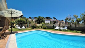 A swimming pool with clear blue water, surrounded by a tiled deck and white lounge chairs. - Fantastic House with Private Pool in Lloret de Mar (Vidreres)