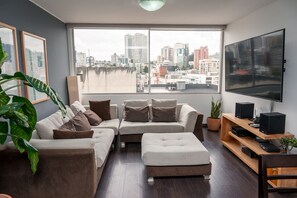 Una sala de estar moderna con un sofá, una mesa de centro, un televisor y un mueble de madera para televisión.