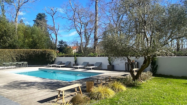 A rectangular swimming pool with lounge chairs and a wooden table on a patio area. - Villa Biarritz / 5 mn plages / Heated pool (Biarritz)