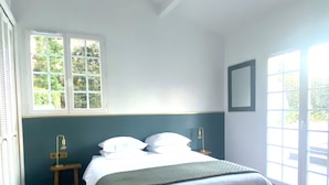 A bedroom with a bed, a window, a bedside table, and a door. - Villa Biarritz / 5 mn plages / Heated pool (Biarritz)