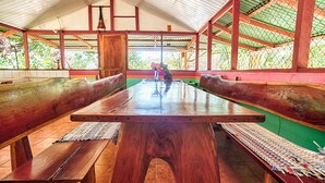 A wooden bench area with a table in the center, surrounded by wooden benches and a green wall.