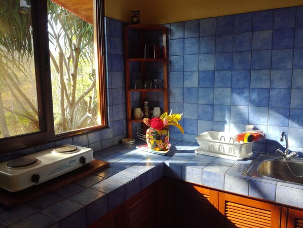 A kitchen with blue tiles, a window, a stove, and a sink.