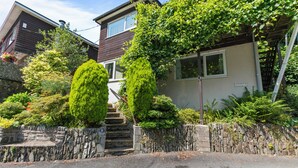 A two-story house with a stone staircase leading to the front door, surrounded by lush greenery and a stone wall. - Two bed Appt. 10 minutes walk to Lynton . Riverside location. EV charge point (Lynton)