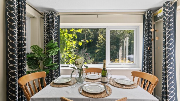 A dining table set for four with a bottle of wine, plates, and cutlery. - Two bed Appt. 10 minutes walk to Lynton . Riverside location. EV charge point (Lynton)