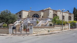 A large, historic building with a prominent arched entrance, a stone facade, and a gated driveway.