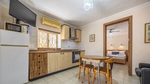 A compact kitchen with wooden cabinets, a microwave, and a dining area with a table and chairs.