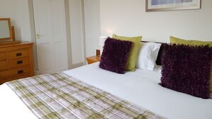 Quarto com cama, duas portas, cômoda e um quadro na parede.
