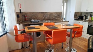 Uma cozinha moderna com mesa de madeira e cadeiras laranja, máquina de lavar e pia.