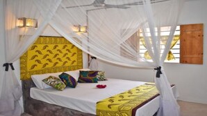 A bed with a canopy, a patterned headboard, and decorative pillows. - Nyumbani Residence- Apartment 3 (Jambiani snc Jambiani)