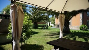 A covered outdoor area with a picnic table, a brick wall, and a palm tree. - CASA GAYOL, NEAR THE BEACH OF PORCÍA (El Franco)