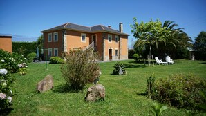 A two-story house with a stone facade, a well-maintained lawn, and outdoor seating. - CASA GAYOL, NEAR THE BEACH OF PORCÍA (El Franco)