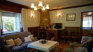 A cozy living room with a fireplace, comfortable seating, and a television. - CASA GAYOL, NEAR THE BEACH OF PORCÍA (El Franco)