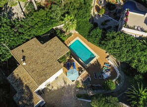 Vista aérea de un resort con piscina, sillones de descanso y una terraza de madera.