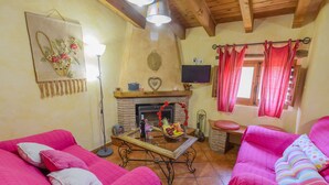 A cozy living room with two pink sofas, a fireplace, a television, and a dining table. - RURAL HOUSE "TENGUERENGUE" (Laroya, Almería)
