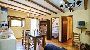 A cozy kitchen with wooden furniture, a dining table, and a TV on a shelf. - Rural house (rental entire) Reul Alto Cortijos Rurales for 2 people (Laroya)