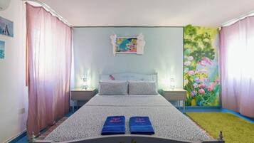 A bedroom with a bed, two nightstands, a painting, and a floral mural.