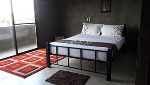 Un dormitorio moderno con una cama, una mesita de noche pequeña y una puerta.