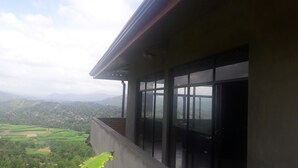 Un balcón con vistas a un paisaje verde y montañas a lo lejos.