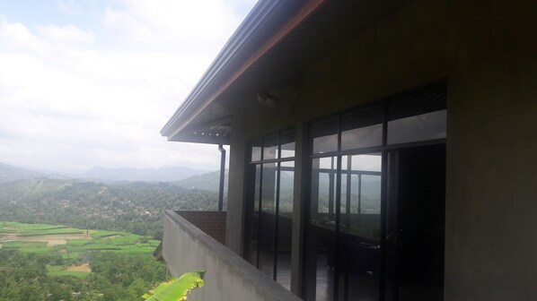 A balcony with a view of a green landscape and distant mountains.
