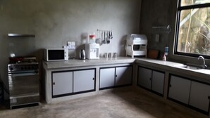 Una cocina con estufa, microondas, cafetera y armarios.
