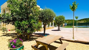 A picnic table in a sandy area with a building in the background and trees around. - Villa los Naranjos Calpe (Calpe)