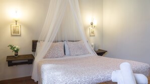 Une chambre à coucher avec un lit à baldaquin, des tables de chevet avec des lampes et une petite plante posée sur une table de nuit.
