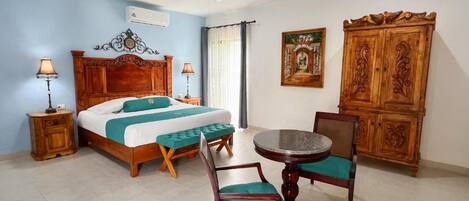 A hotel room with a bed, a round table with chairs, a ceiling fan, and a wooden cabinet.