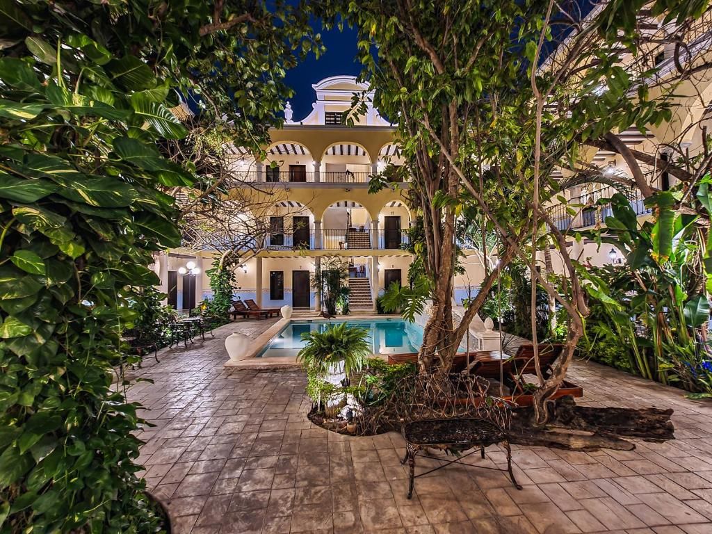 A courtyard with a pool, surrounded by lush greenery and a building with multiple balconies.