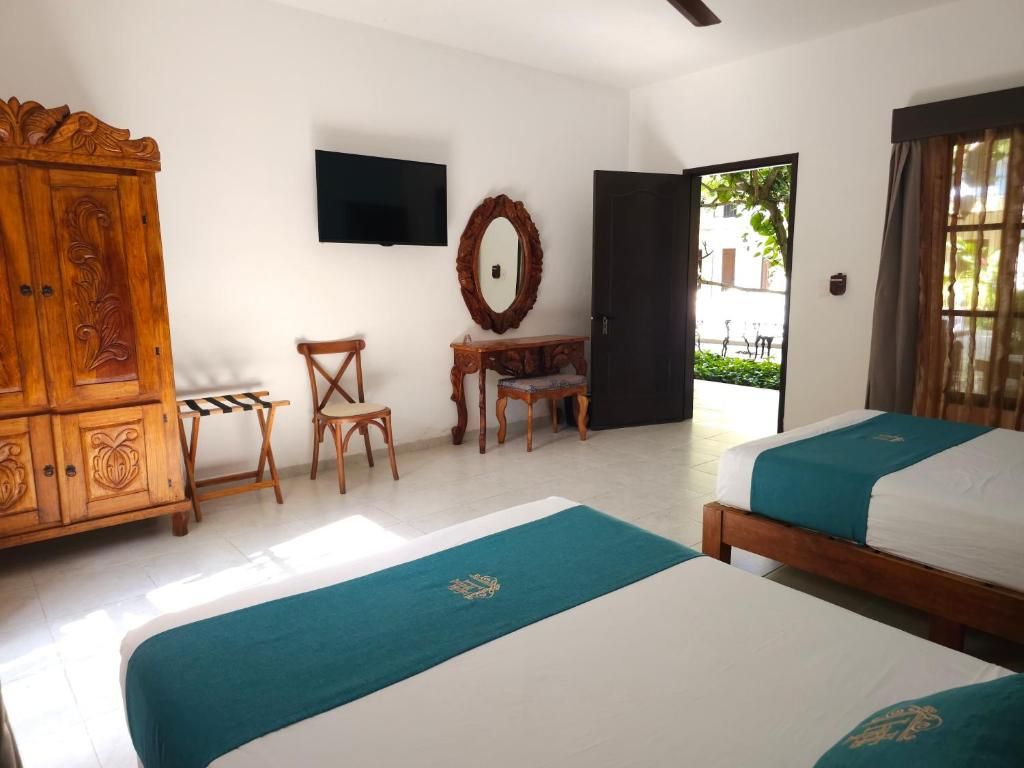 Une chambre d’hôtel avec deux lits, une armoire en bois, un bureau et un téléviseur.