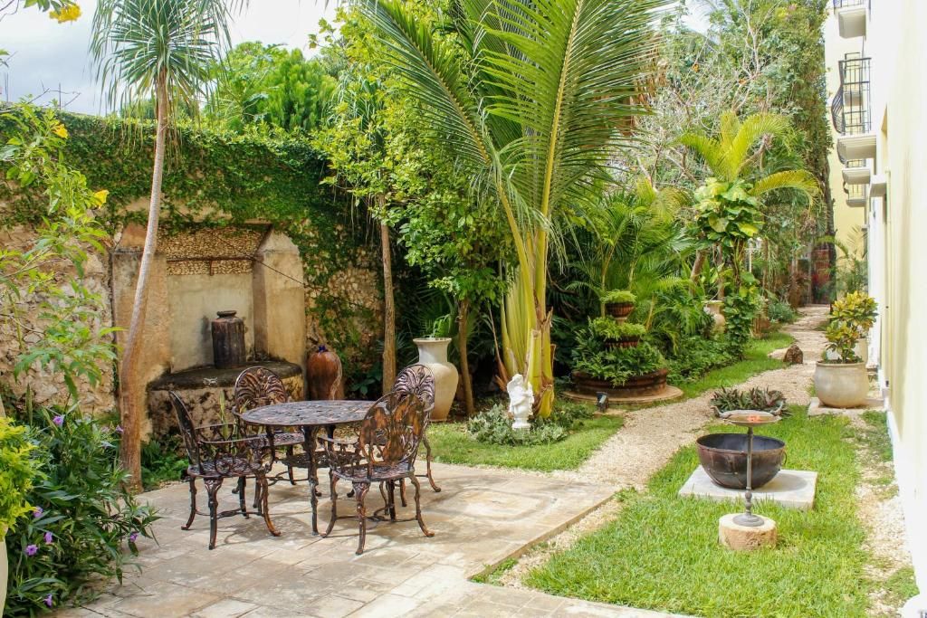 A patio with a table and chairs, surrounded by lush greenery and a variety of plants.