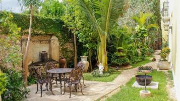 A patio with a table and chairs, surrounded by lush greenery and a variety of plants.